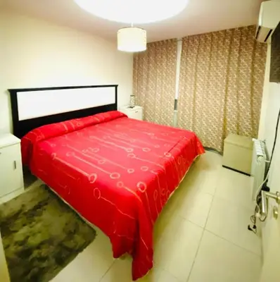a bedroom with a red bed in a room at Departamento Centrico Eutico in Villa Carlos Paz