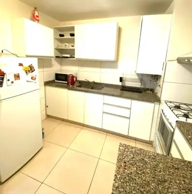 a kitchen with white cabinets and a white refrigerator at Departamento Centrico Eutico in Villa Carlos Paz