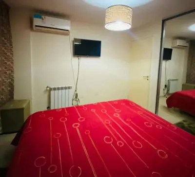 a red bed in a room with a mirror at Departamento Centrico Eutico in Villa Carlos Paz