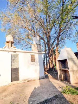 a white building with a chimney and a tree at Casa Ramona in Embalse