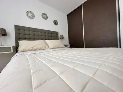 a large white bed in a bedroom with clocks on the wall at Urban Alberdi Dpto con cochera, pileta y seguridad 24 hs in Cordoba