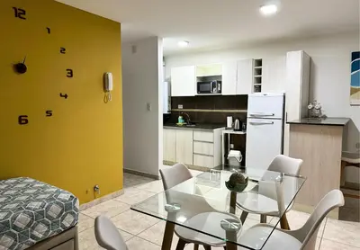 a kitchen and dining room with a glass table and chairs at Urban Alberdi Dpto con cochera, pileta y seguridad 24 hs in Cordoba