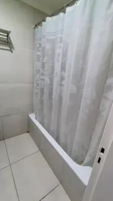 a bathroom with a shower with a white shower curtain at Departamento Atardecer de Rio Cuarto in Río Cuarto
