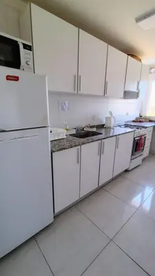 a kitchen with white cabinets and a white refrigerator at Departamento Atardecer de Rio Cuarto in Río Cuarto
