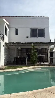 a house with a swimming pool in front of a house at Casa Guemes, pet friendly in Villa Carlos Paz