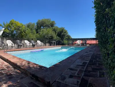 a pool with chairs and a table in a yard at Complejo Don H in Villa Carlos Paz