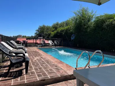a swimming pool with chairs and a table and a table and a tablektop at Complejo Don H in Villa Carlos Paz