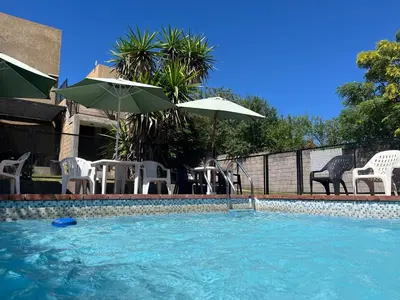 a swimming pool with chairs and umbrellas next to at Complejo Don H in Villa Carlos Paz