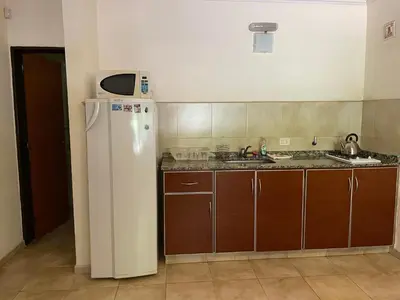 a kitchen with a white refrigerator and wooden cabinets at Complejo Don H in Villa Carlos Paz