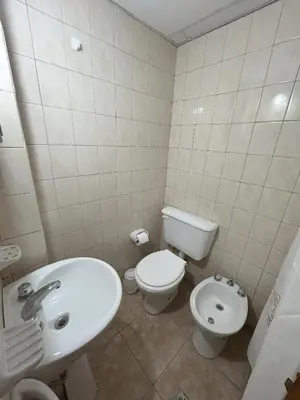 a white bathroom with a toilet and a sink at Apart Geranio, monoambiente en planta baja in Río Cuarto