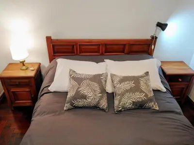 a bed with three pillows and a lamp on a table at Departamento en zona centro La Cañada para 2 personas in Cordoba