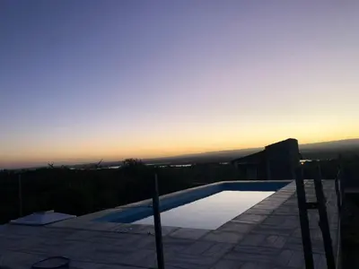 a swimming pool with the sunset in the background at Ludqui in Villa Rumipal