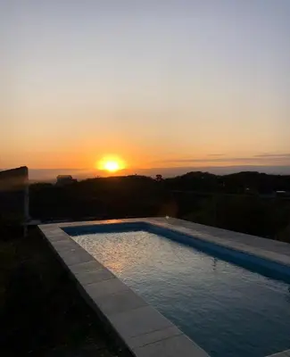 a swimming pool with the sunset in the background at Ludqui in Villa Rumipal
