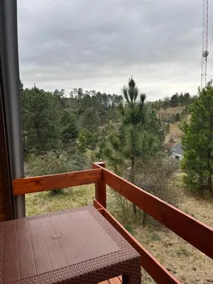 a balcony with a table and a view of a forest at Aire Escondido in Villa Berna