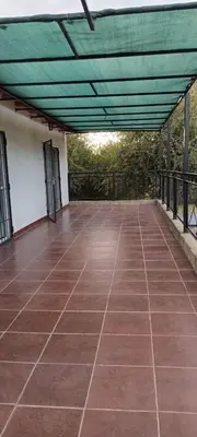 a patio with a green roof and a tile floor at Hospedaje Miraflor in Cerro de Oro