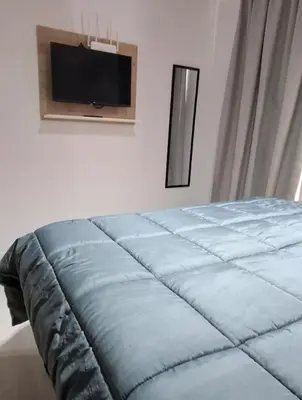 a bed in a bedroom with a tv on the wall at Miralejos 16 Turquesa in Villa Carlos Paz