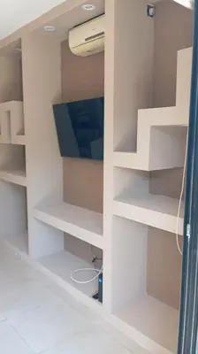 a room with a tv and white shelves at Dpto Premium Costanera Pileta y Cochera in Villa Carlos Paz