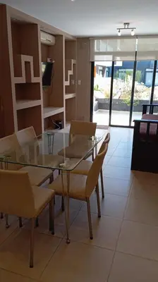 a dining room with a glass table and chairs at Dpto Premium Costanera Pileta y Cochera in Villa Carlos Paz