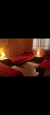 a bedroom with two beds with red sheets and a window at La casa de los Nonos in Mina Clavero