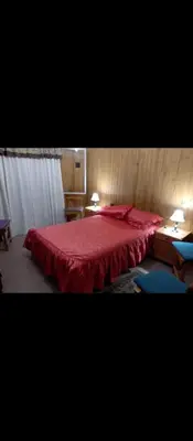 a bedroom with a bed with a red bedspread at La casa de los Nonos in Mina Clavero