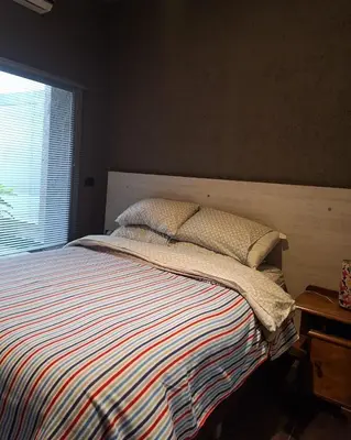 a bedroom with a bed with a striped blanket and a window at Modern PH with Grill in Cordoba