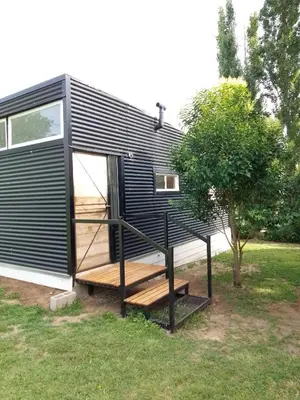 a black tiny house with a staircase next to a tree at Tiny House Potrero Cba in Potrero de Garay