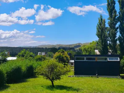 a house in a field with a tree at Tiny House Potrero Cba in Potrero de Garay