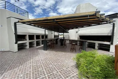 a patio with tables and chairs under awning on a building at Departamento Céntrico Miralejos 3 in Villa Carlos Paz