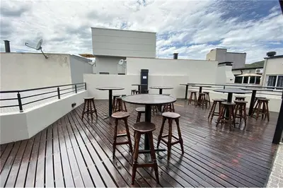 a group of tables and stools on a rooftop deck at Departamento Céntrico Miralejos 3 in Villa Carlos Paz
