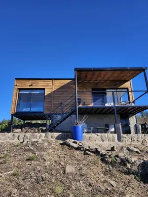 a house on top of a hill with a blue pot at Brisas de la Cayana Cabaña Villa Alpina in Villa Alpina
