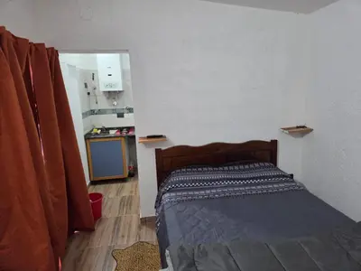 a small bedroom with a bed and a kitchen at Lusanyun in Villa Carlos Paz