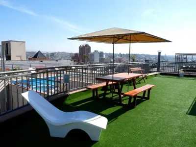 a balcony with a table and benches and an umbrella at Departamento Céntrico Miralejos 2 in Villa Carlos Paz