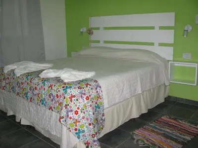 a bedroom with a bed with a white bedspread and avertisement at Balcones de Los Chorrillos in Estancia Vieja
