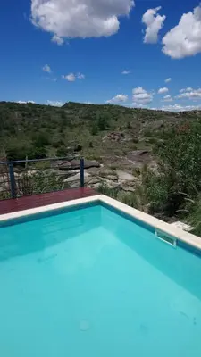 a blue swimming pool with a view of a hill at Balcones de Los Chorrillos in Estancia Vieja