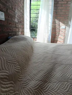 a bed in a room with a brick wall at CASA EL GRINGO ubicada en Villa Parque Siquiman con vista al río tres habitaciones y capacidad para ocho personas in Villa Parque Siquiman