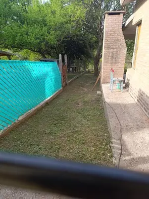 a backyard with a blue fence next to a house at CASA EL GRINGO ubicada en Villa Parque Siquiman con vista al río tres habitaciones y capacidad para ocho personas in Villa Parque Siquiman
