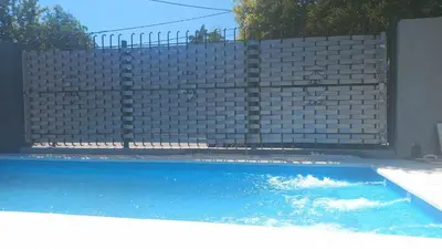 a swimming pool in front of a brick fence at La casita in Villa Carlos Paz