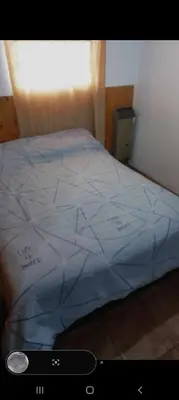 a bed with a blue comforter in a room at La casita in Villa Carlos Paz