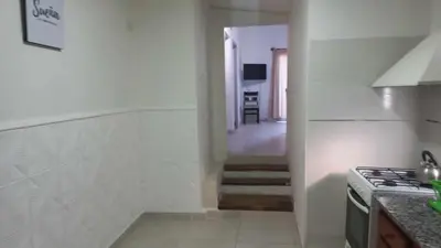 a white kitchen with a stove and a hallway at La casita in Villa Carlos Paz