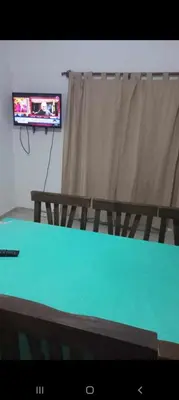 a television in a room with a table and a curtain at La casita in Villa Carlos Paz