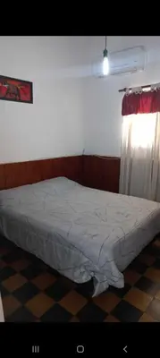 a bedroom with a bed and a window with a curtain at La casita in Villa Carlos Paz