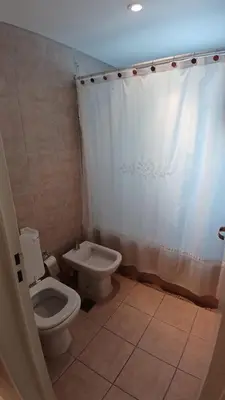 a bathroom with a toilet and a white shower curtain at Cordoba temporario in Cordoba