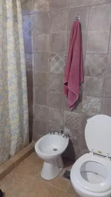 a bathroom with a toilet and a towel on the wall at Cabaña Zara in Villa Yacanto