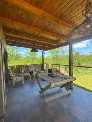 a picnic table on a porch with a wooden roof at Cabaña Zara in Villa Yacanto