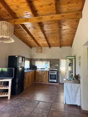 a kitchen with a black refrigerator and wooden ceilings at Cabaña Zara in Villa Yacanto