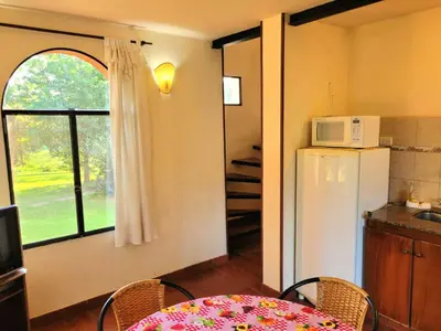 a kitchen with a table and a refrigerator and a window at Cabañas El Paso in Villa del Dique