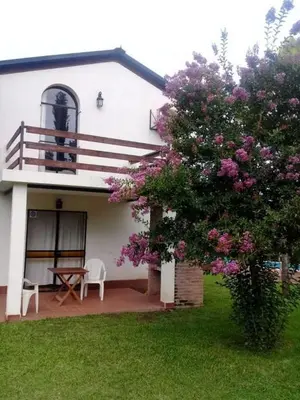 a house with a balcony and a tree with purple flowers at Cabañas El Paso in Villa del Dique