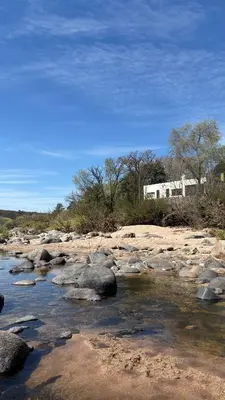 a river with rocks and a building in the background at Casa con vista y acceso al río in Villa Icho Cruz