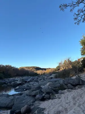 a river with rocks and trees and a blue sky at Casa con vista y acceso al río in Villa Icho Cruz