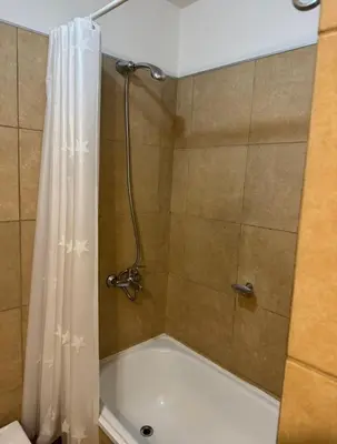 a shower with a white shower curtain and a tub at Departamento un dormitorio Frente al Pocito in Cordoba